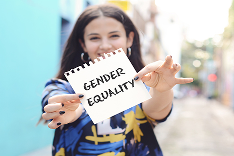 This is a stock photo. A woman holding a sign which reads "gender equality."